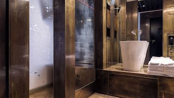 Un baño moderno con un espejo grande, un lavabo blanco y una pila de toallas.