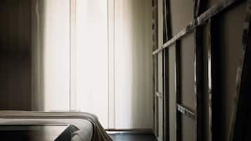 A room with a bed, a window with sheer curtains, and a wooden wall.