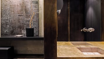 Een moderne badkamer met een grote spiegel, een houten kastje en een structuurwand.