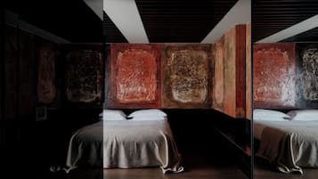 Une chambre d’hôtel moderne avec un grand lit, un miroir et des œuvres d’art abstrait accrochées aux murs.