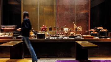 A buffet area with various food items and a person walking.