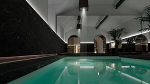 A modern indoor swimming pool with a clear water surface, surrounded by dark marble walls and minimalist architecture. - Straf, Milan, a Member Of Design Hotels (Milan)