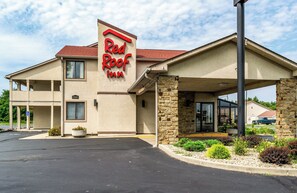 Un hôtel Red Roof Inn avec une façade beige, des piliers en pierre et une entrée abritée.