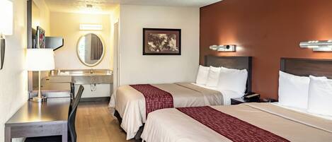 A hotel room with two beds, a desk, a chair, a mirror, and a picture on the wall.