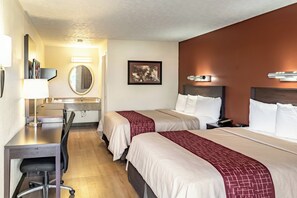 Ein Hotelzimmer mit zwei Betten, einem Schreibtisch, einem Stuhl, einem Spiegel und einem Bild an der Wand.