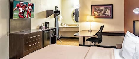 Une chambre d’hôtel équipée d’un lit, d’un bureau, d’une chaise, d’une télévision, d’un miroir et d’une lampe.