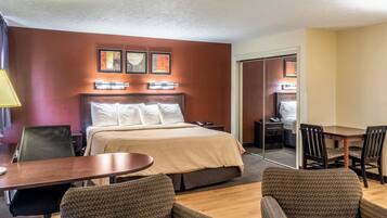 A hotel room with a bed, a desk, two chairs, and a mirror.