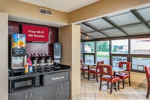 Un restaurante con estación de café, un letrero que indica acceso a Wi-Fi gratuito y vistas al estacionamiento.
