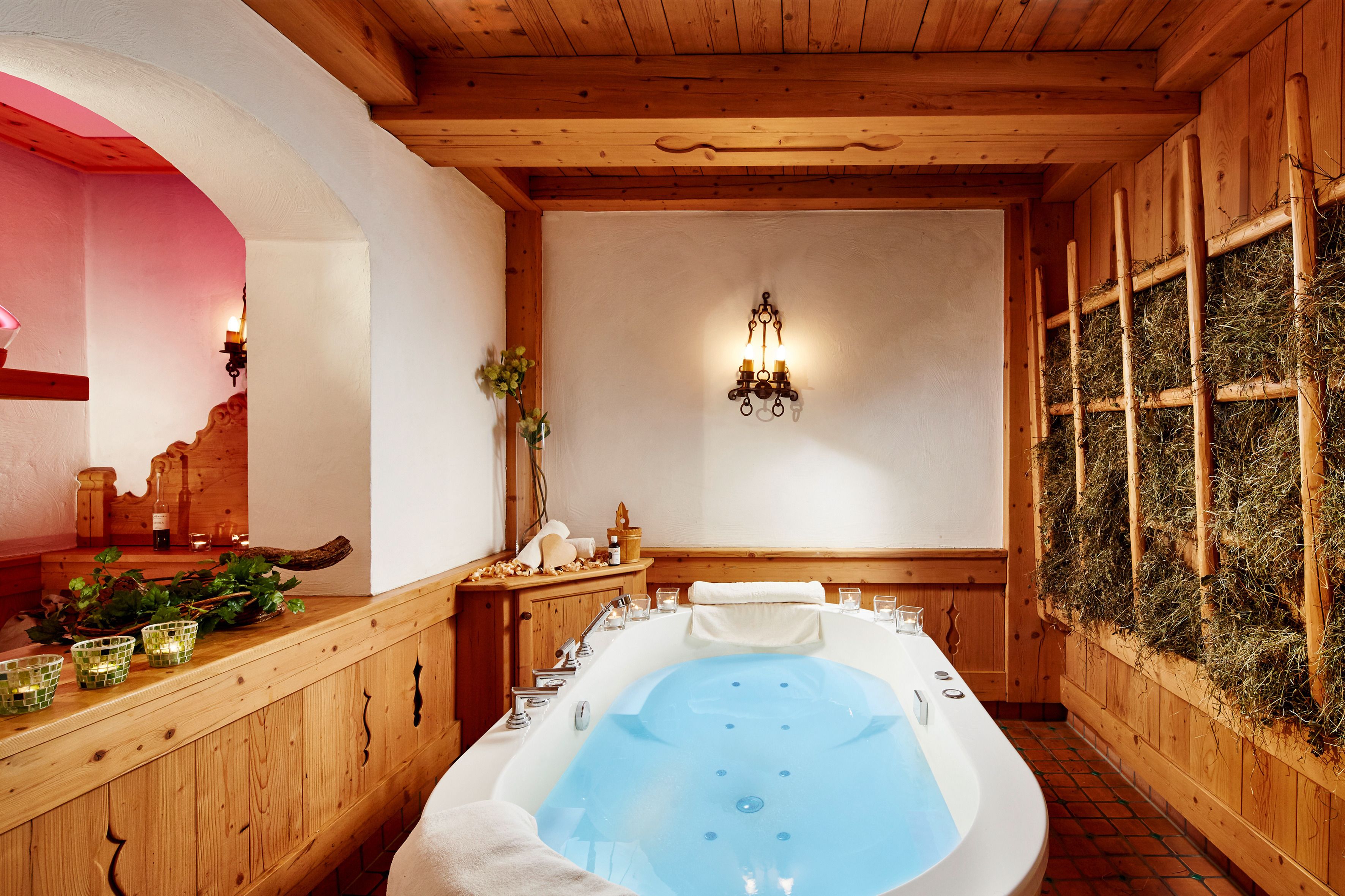 Un cuarto de spa con una bañera grande, paredes de madera y una lámpara de pared.