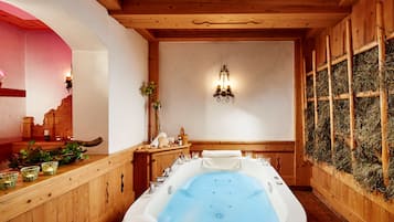 Un cuarto de spa con una bañera grande, paredes de madera y una lámpara de pared.