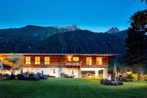 Une maison moderne en bois dotée d’un grand balcon, d’un espace salon extérieur et offrant une vue sur les montagnes.