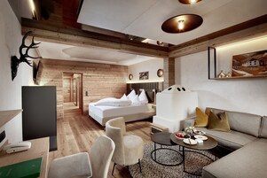 Une chambre d’hôtel moderne avec un plafond en bois, un lit avec une literie blanche, un canapé, une table basse et un téléviseur.