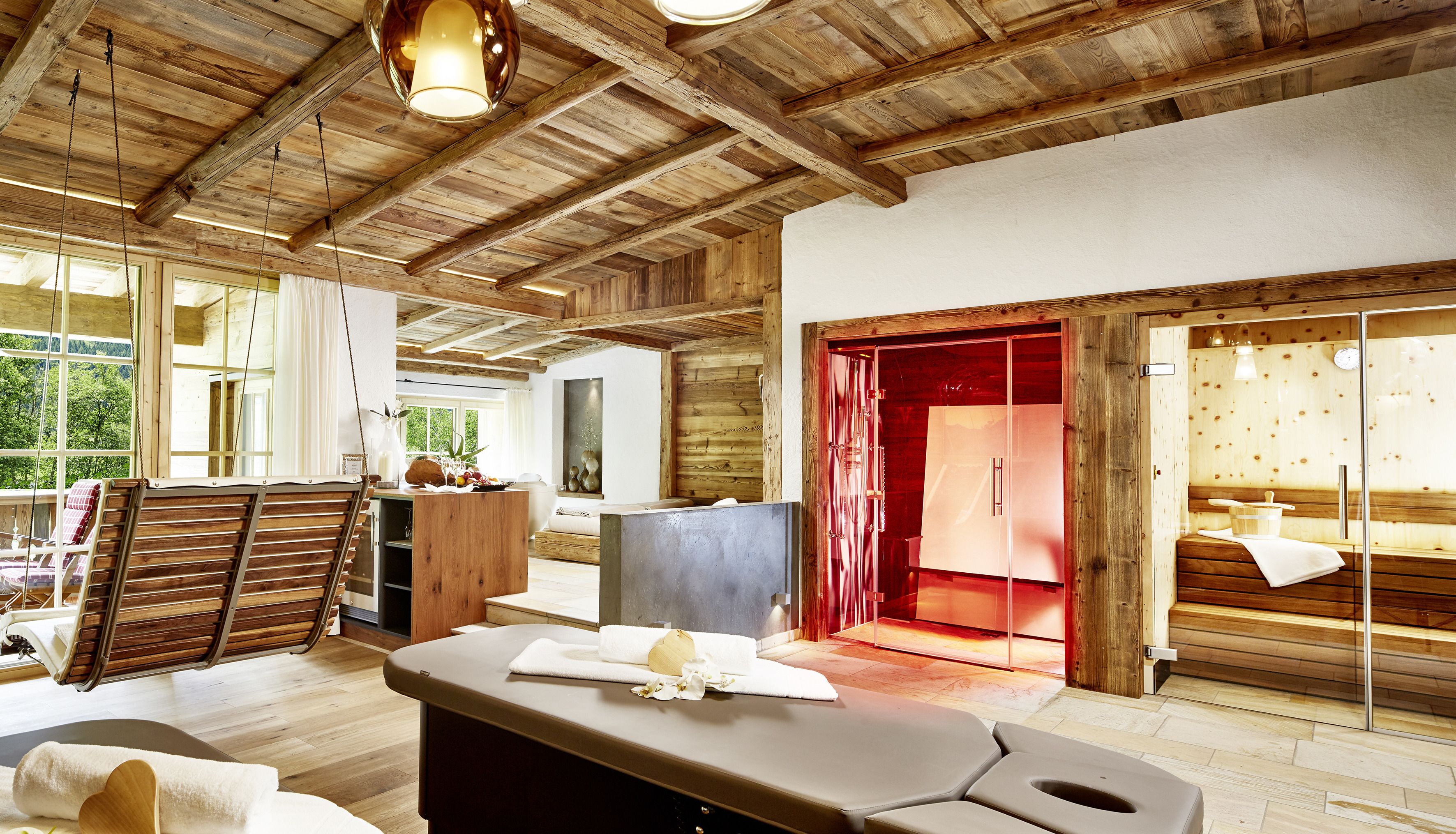 Una habitación amplia con vigas de madera, zona de sauna y vistas al exterior.