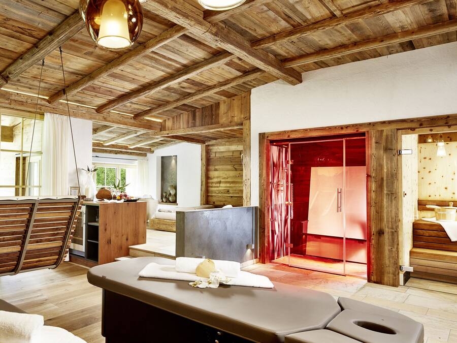 A spacious room with wooden beams, a sauna area, and a view of the outdoors.