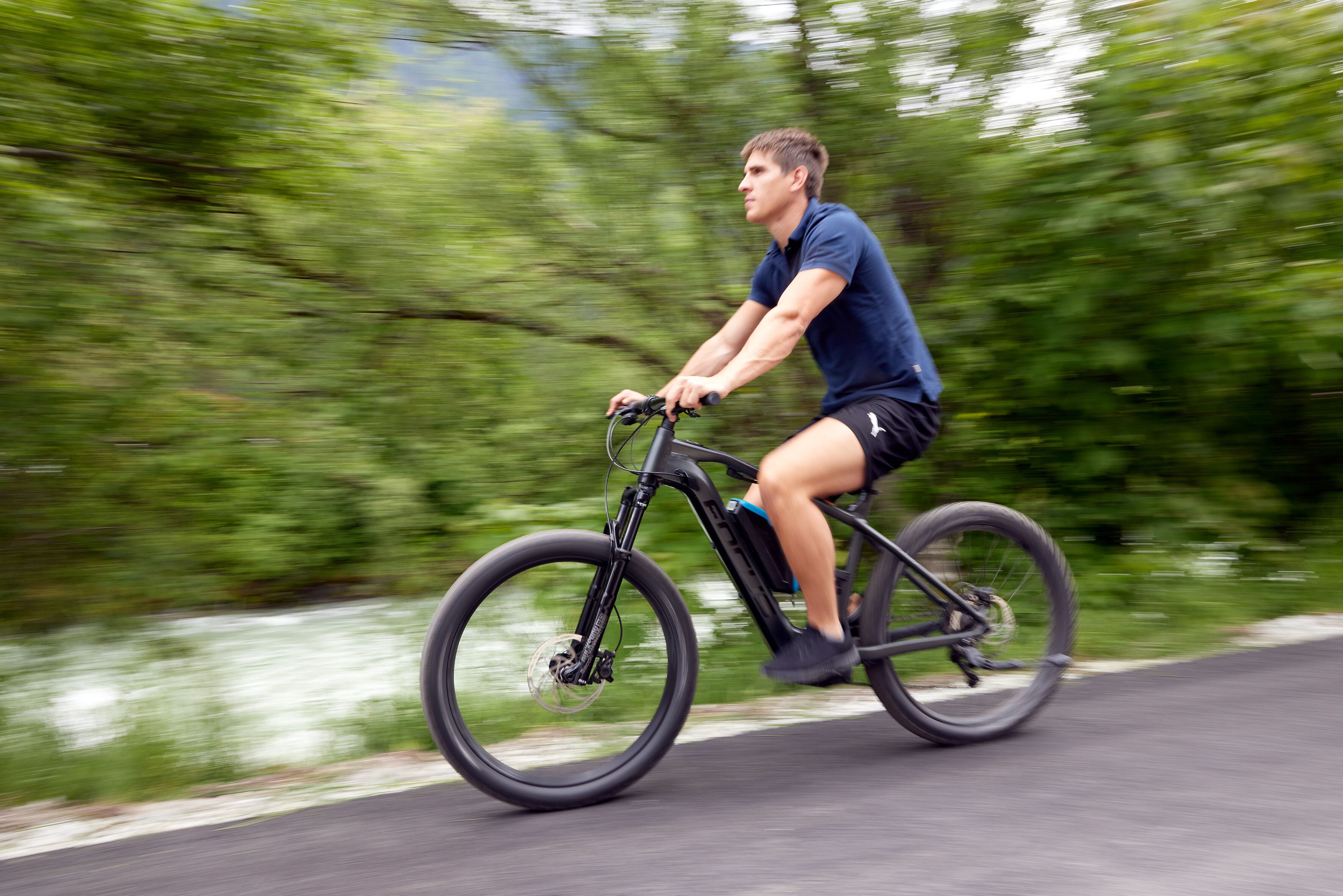A person riding a bicycle on a road with greenery on the sides.