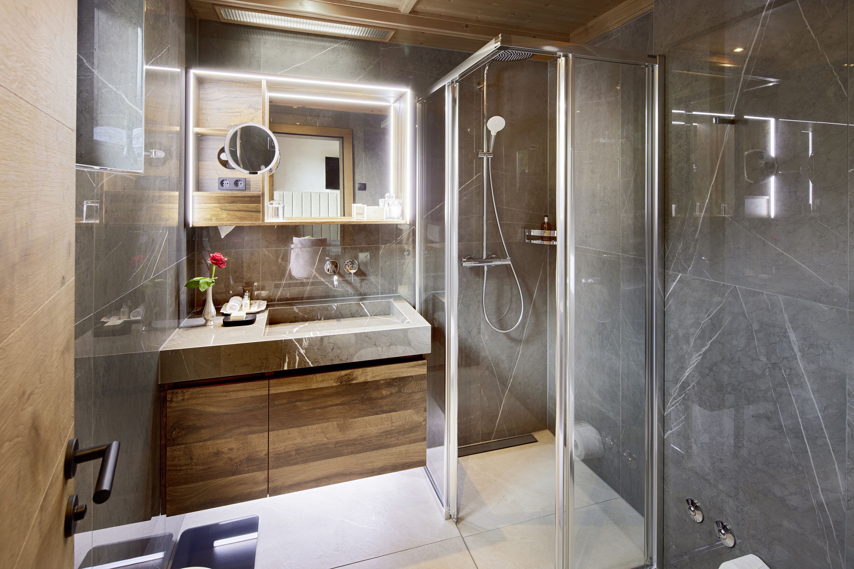 A modern bathroom with a glass-enclosed shower, a vanity with a mirror, and a wooden cabinet.