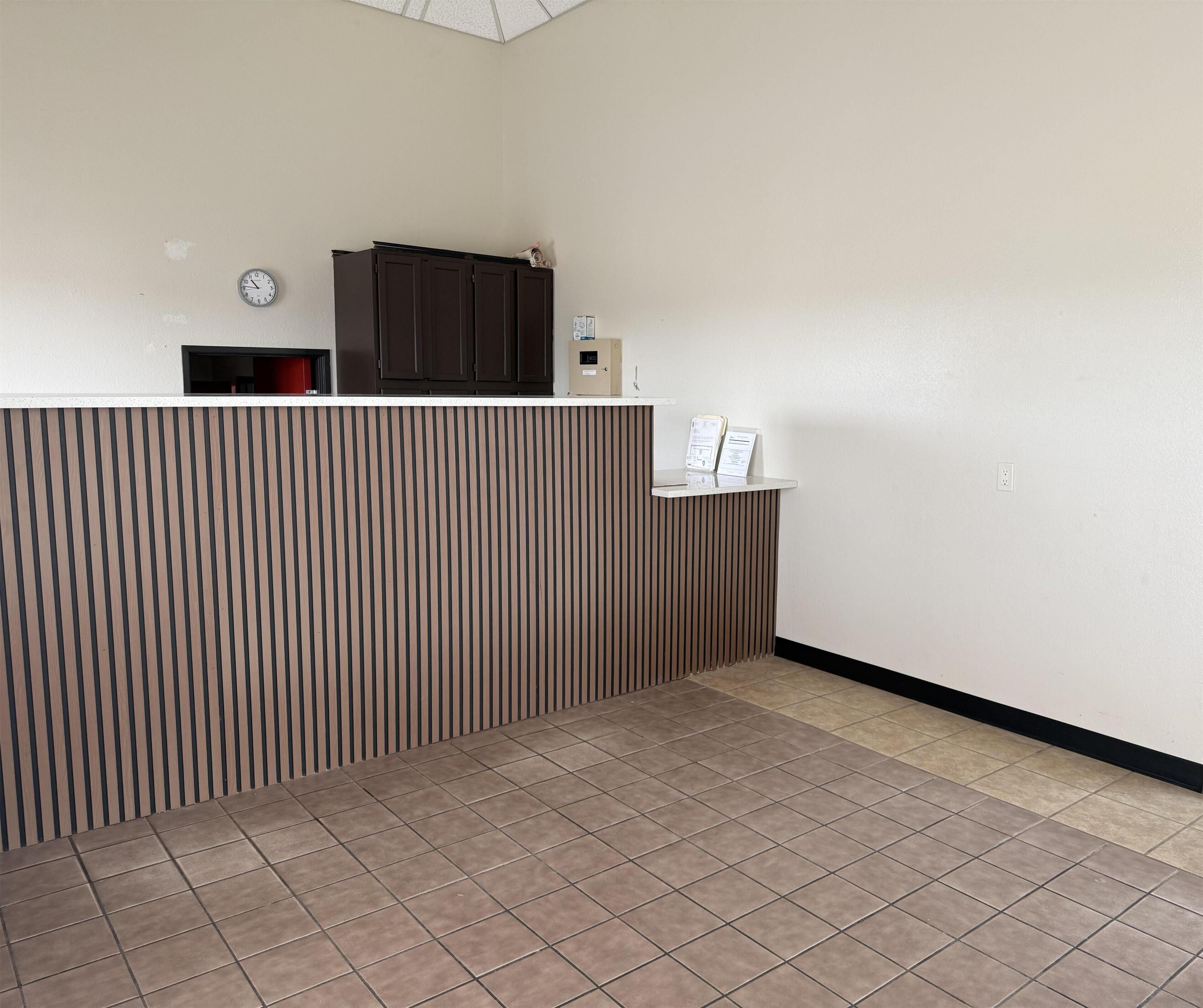 A reception desk with a clock, a bulletin board, and a dark wooden paneling.