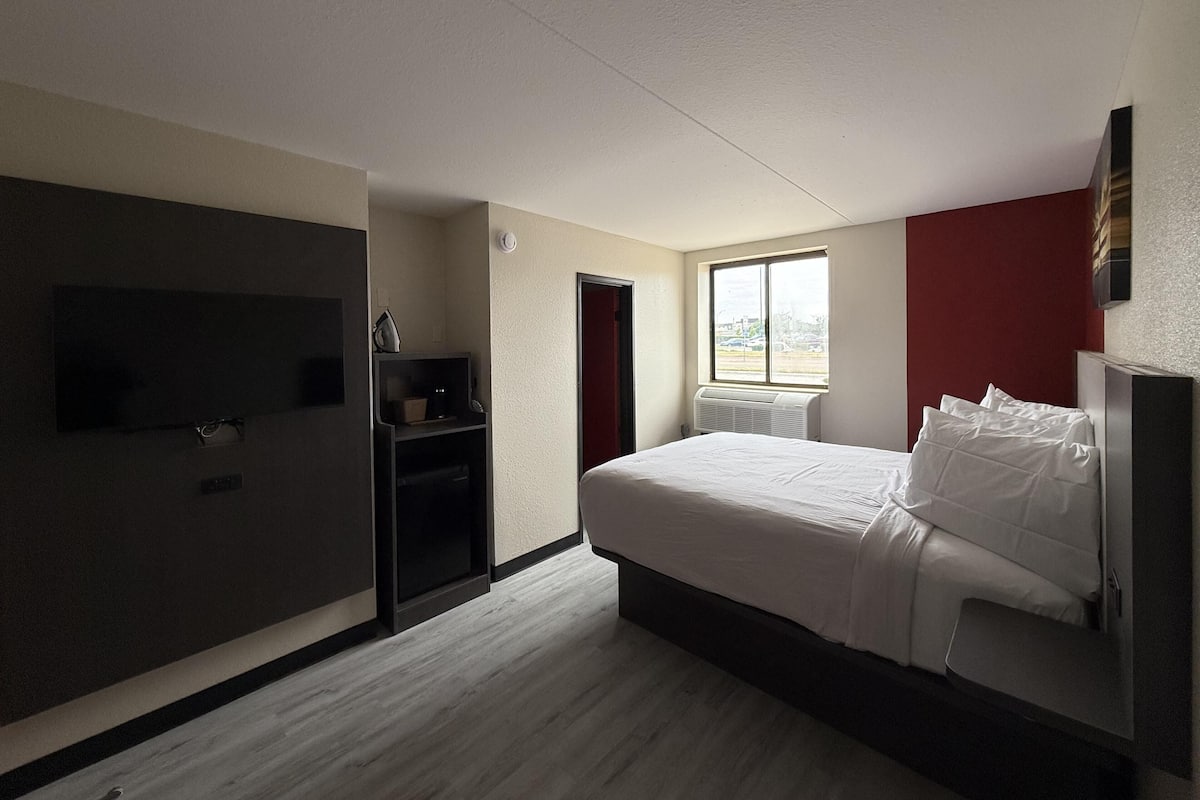 Quarto com cama, televisão, aquecedor e janela.