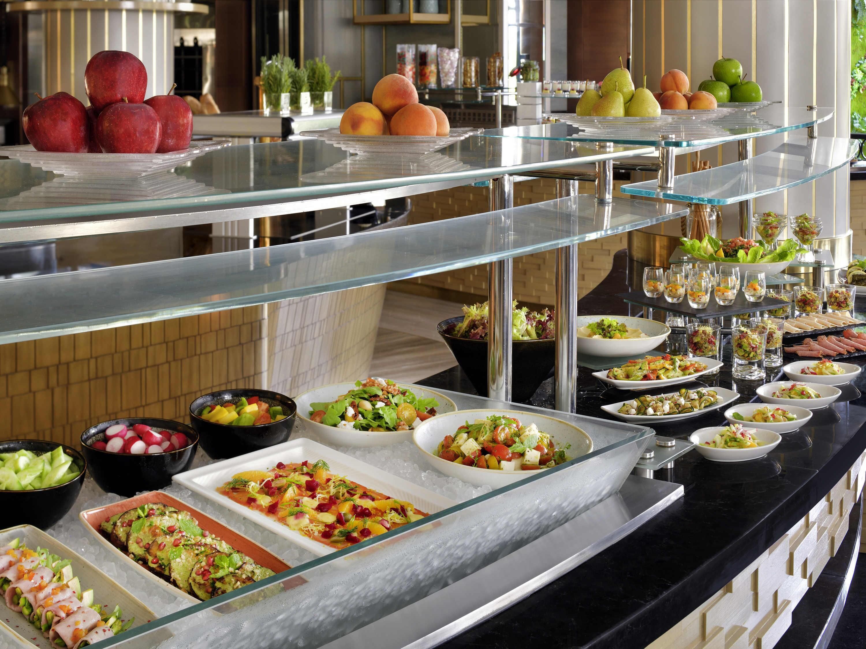 A buffet with various food options including fruits, salads, and appetizers.