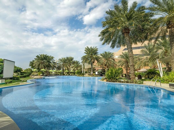 Outdoor pool, pool umbrellas, sun loungers - Mövenpick Hotel Bahrain (Muharraq)