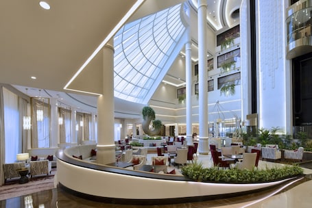 A spacious lobby with a high ceiling, a central seating area, and a large skylight.