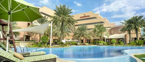 Alberca al aire libre, sombrillas en la alberca y camastros