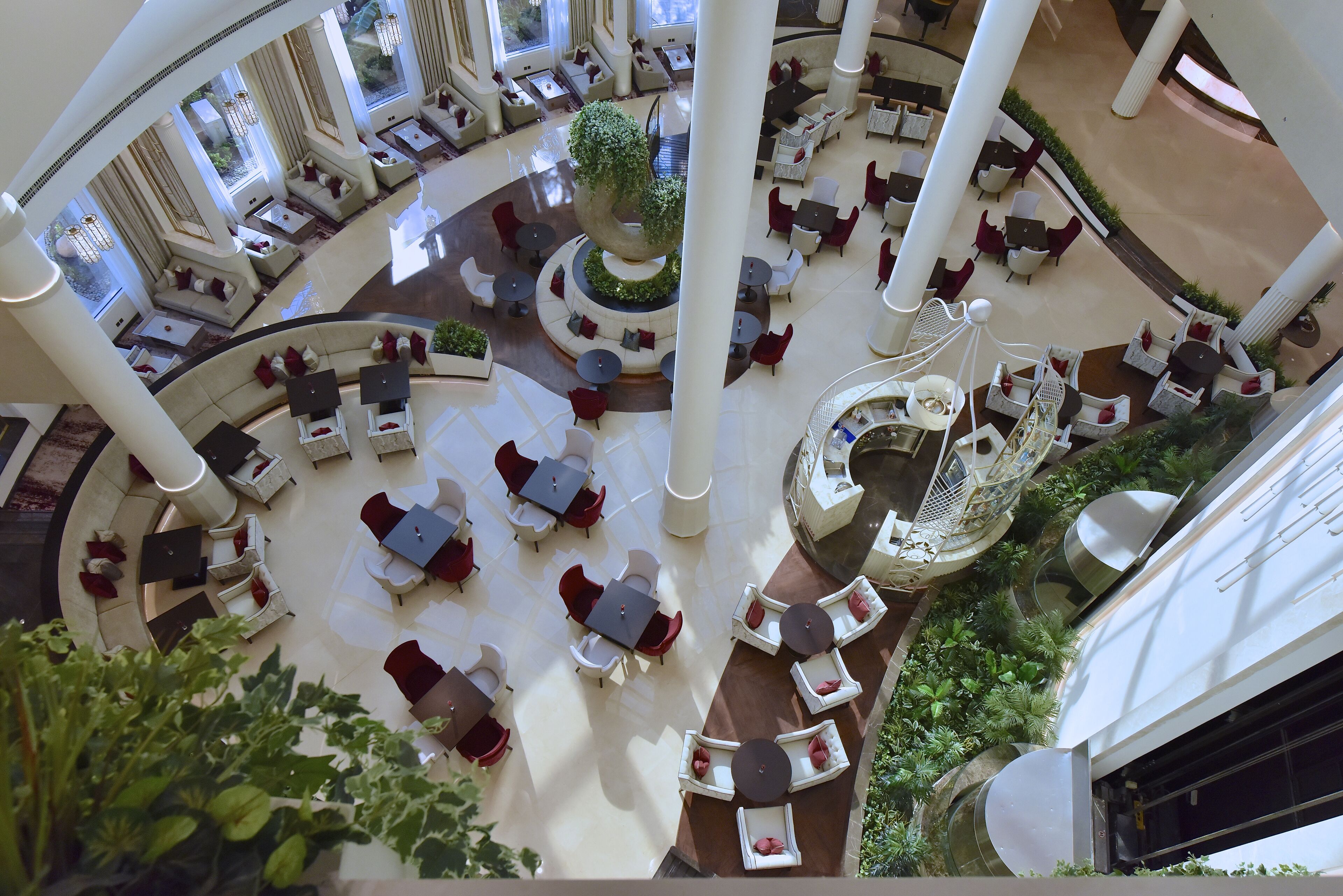 A spacious atrium with multiple seating areas, a central decorative tree, and a spiral staircase.