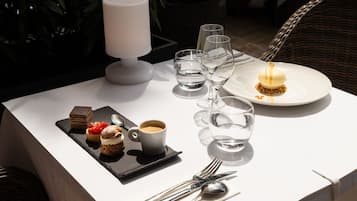 Une table à manger avec une assiette à dessert, une tasse de café et un plateau de pâtisseries.