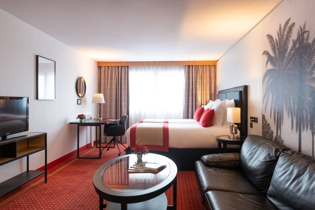 Una habitación de hotel con cama, televisión, escritorio, sofá y mesa de centro.