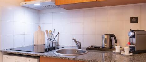 A modern kitchen with a dishwasher, sink, microwave, kettle, and coffee maker.