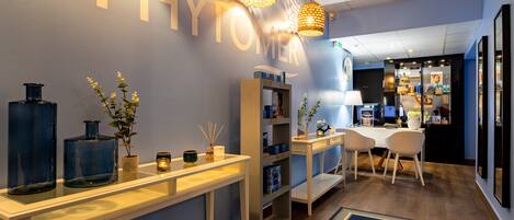 Un lobby moderno de hotel con un mostrador de recepción, una zona de estar y una pared con la palabra "PHYTO" iluminada.