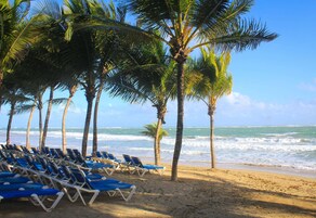 Na praia, areia branca, espreguiçadeiras, toalhas de praia 