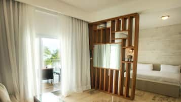 A hotel room with a bed, a glass coffee table, a wooden partition, and a view of the outdoors.