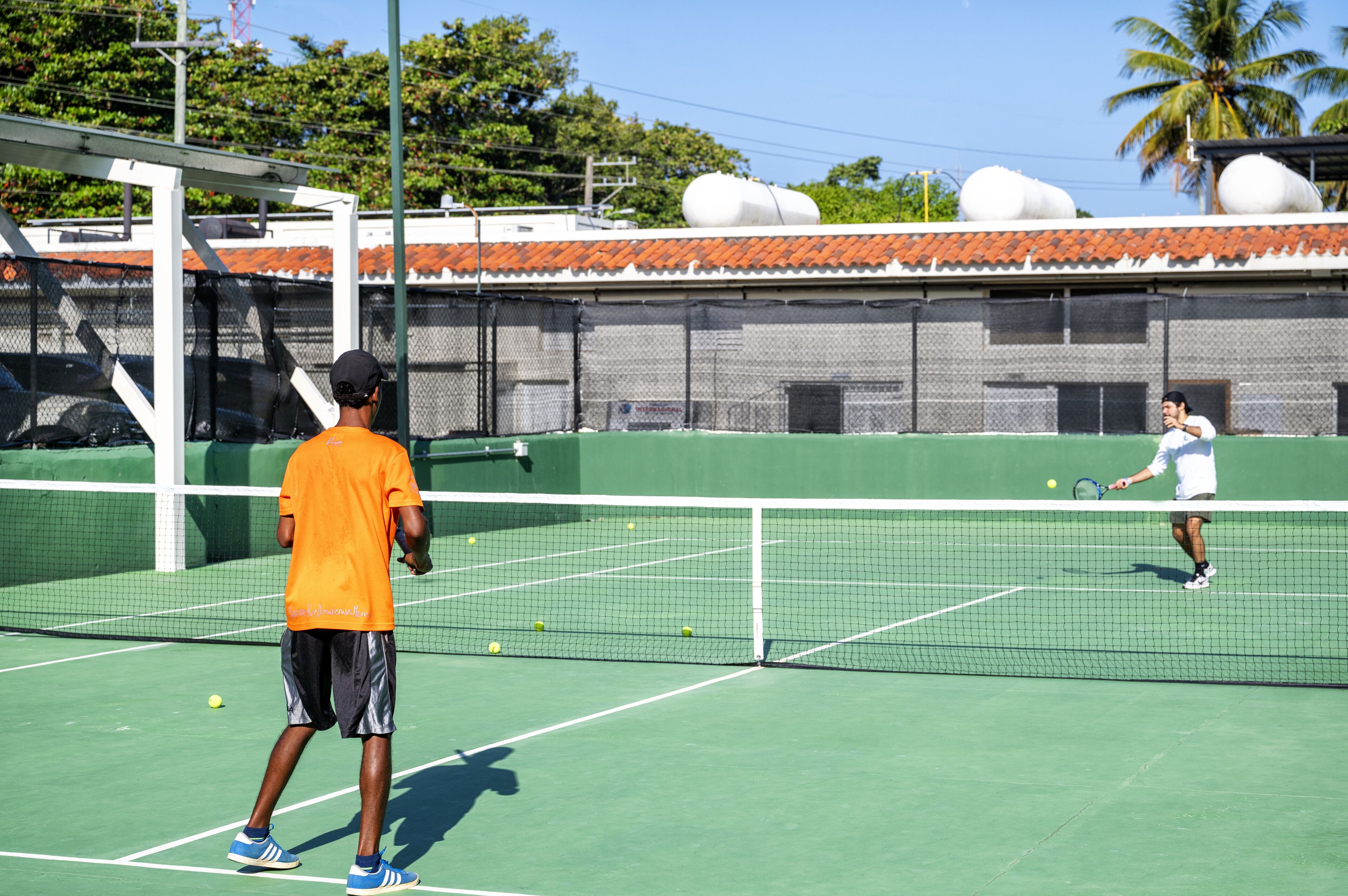 A tennis court with a net, two players, and a green playing surface.