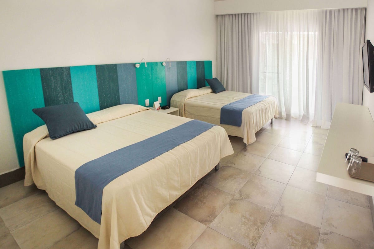 Ein Hotelzimmer mit zwei Betten, einem Schreibtisch und einem Fernseher.
