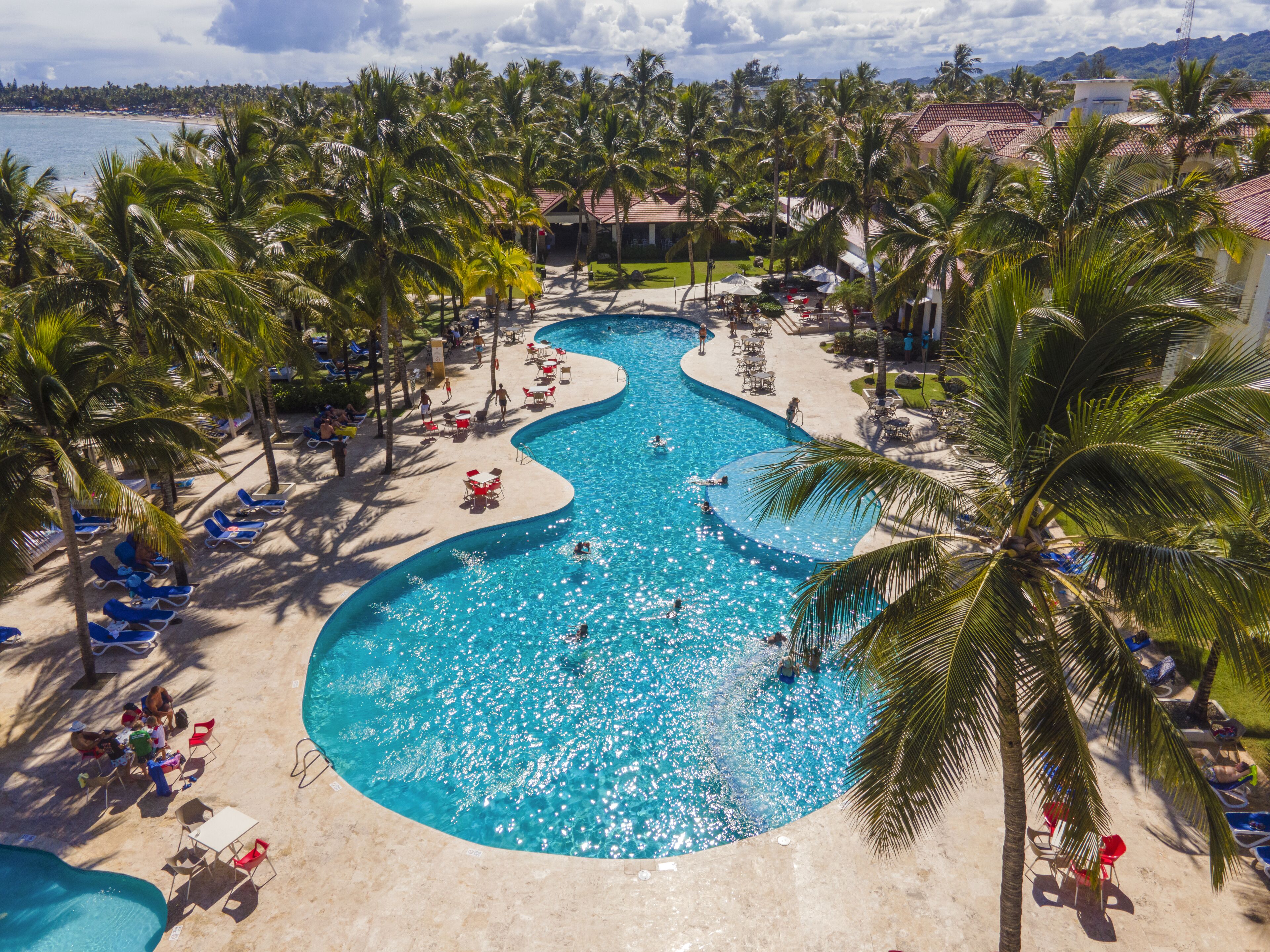 A resort with a large, winding pool surrounded by palm trees and lounge chairs.