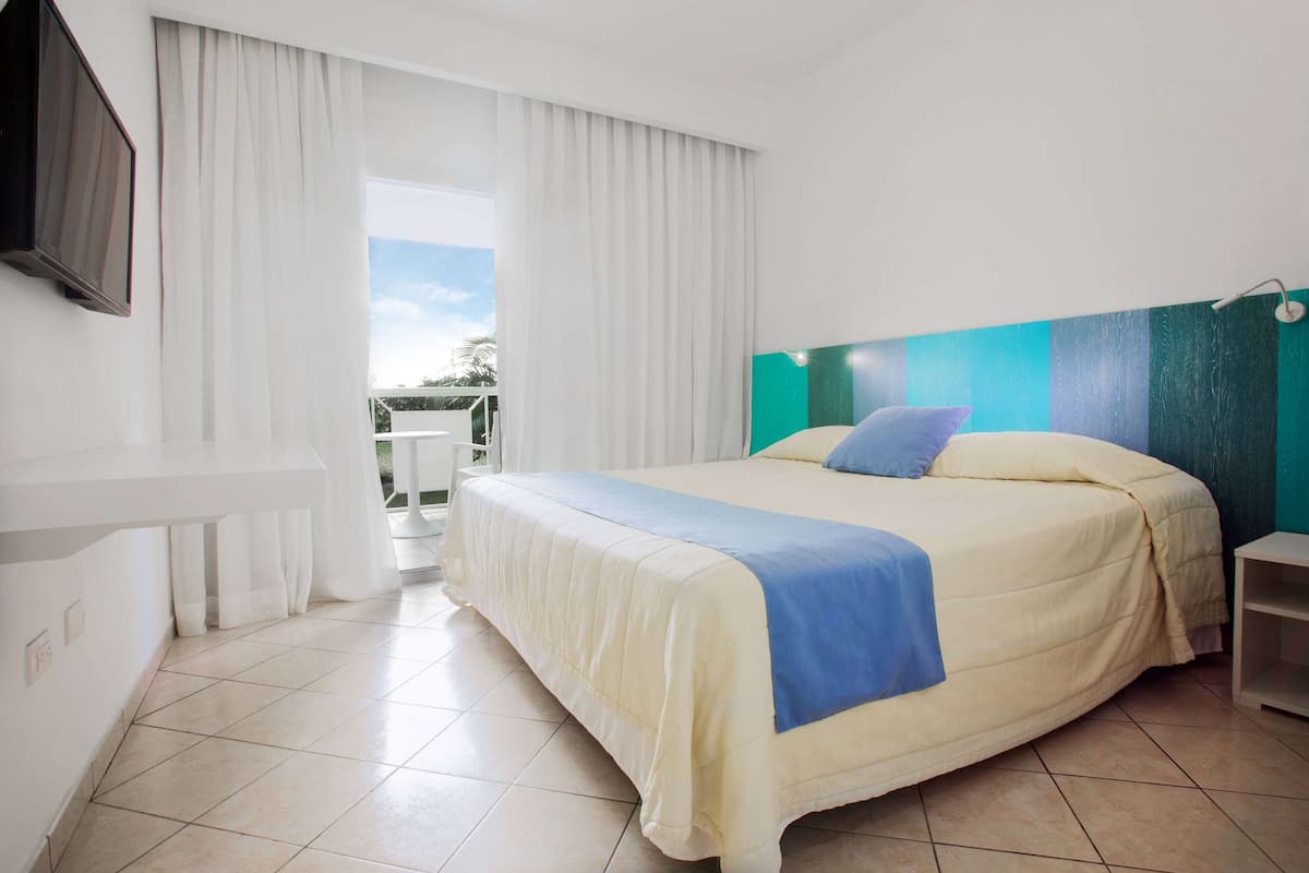 Ein Hotelzimmer mit Bett, Fernseher und Blick ins Freie.