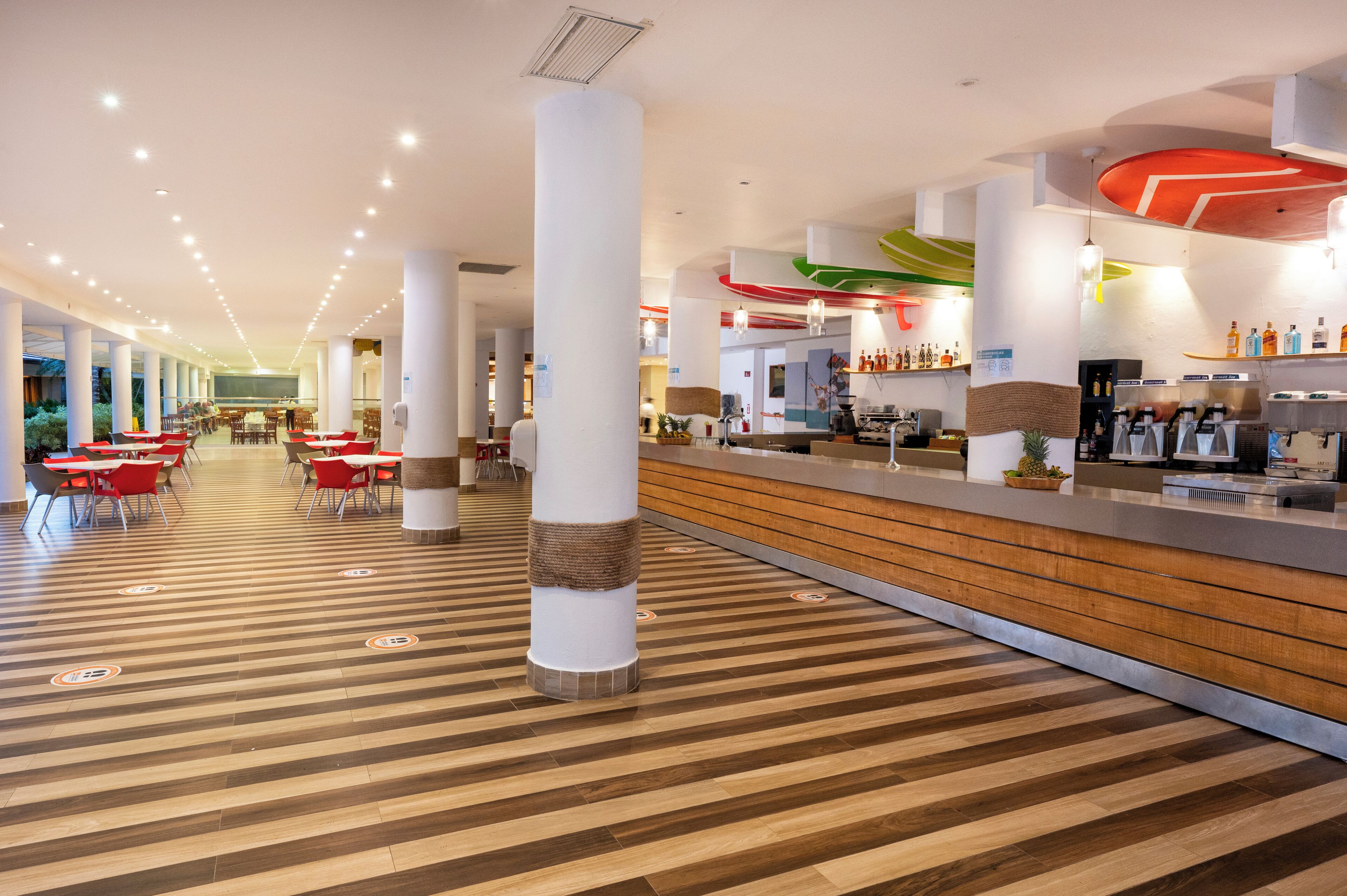 Eine geräumige Lobby mit Holzboden, roten Stühlen, einem Empfangstresen und einer Bar.