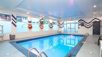 An indoor swimming pool with clear blue water, tiled walls, and a ceiling with recessed lighting.