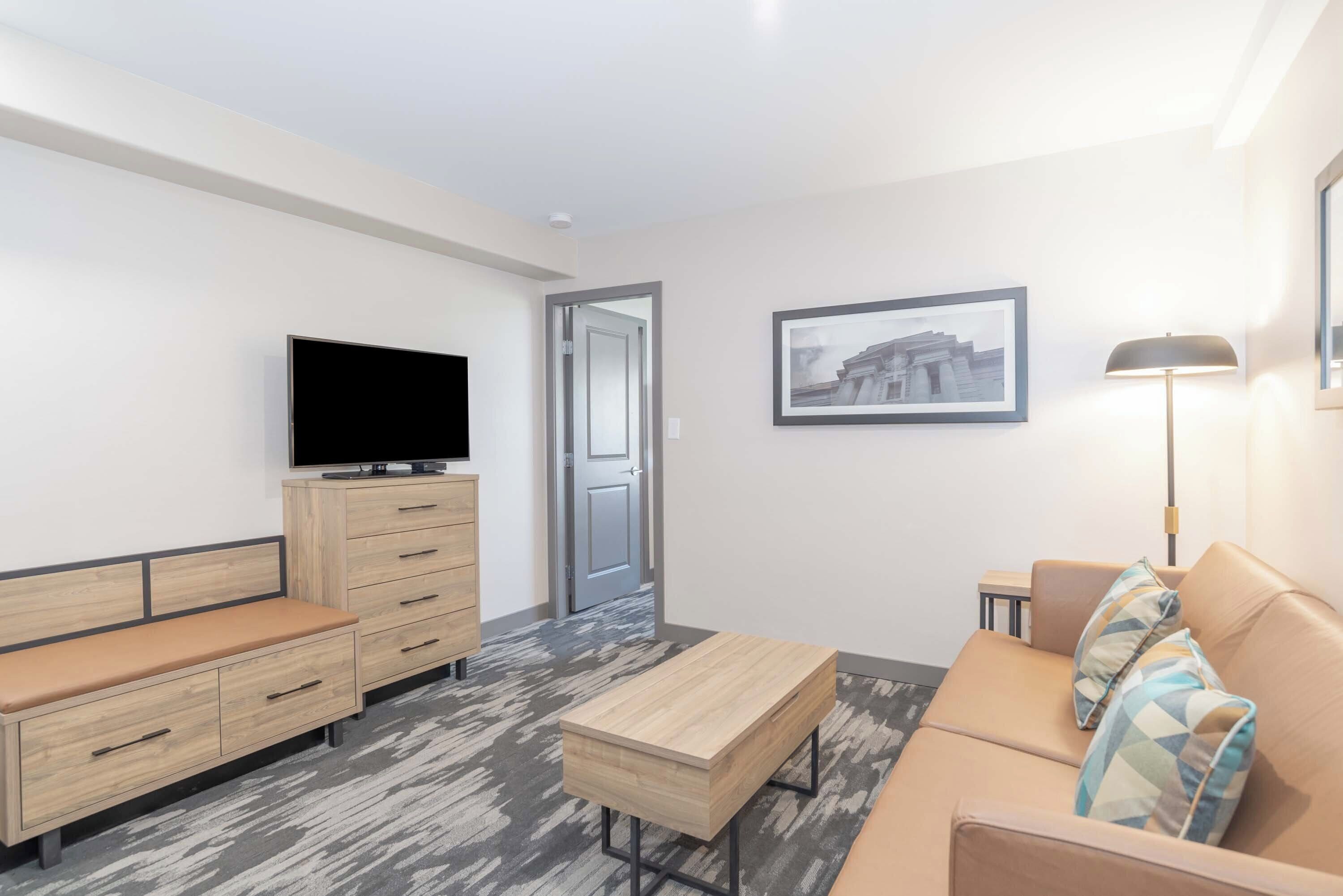 A modern living room with a sofa, a coffee table, a TV, and a desk.