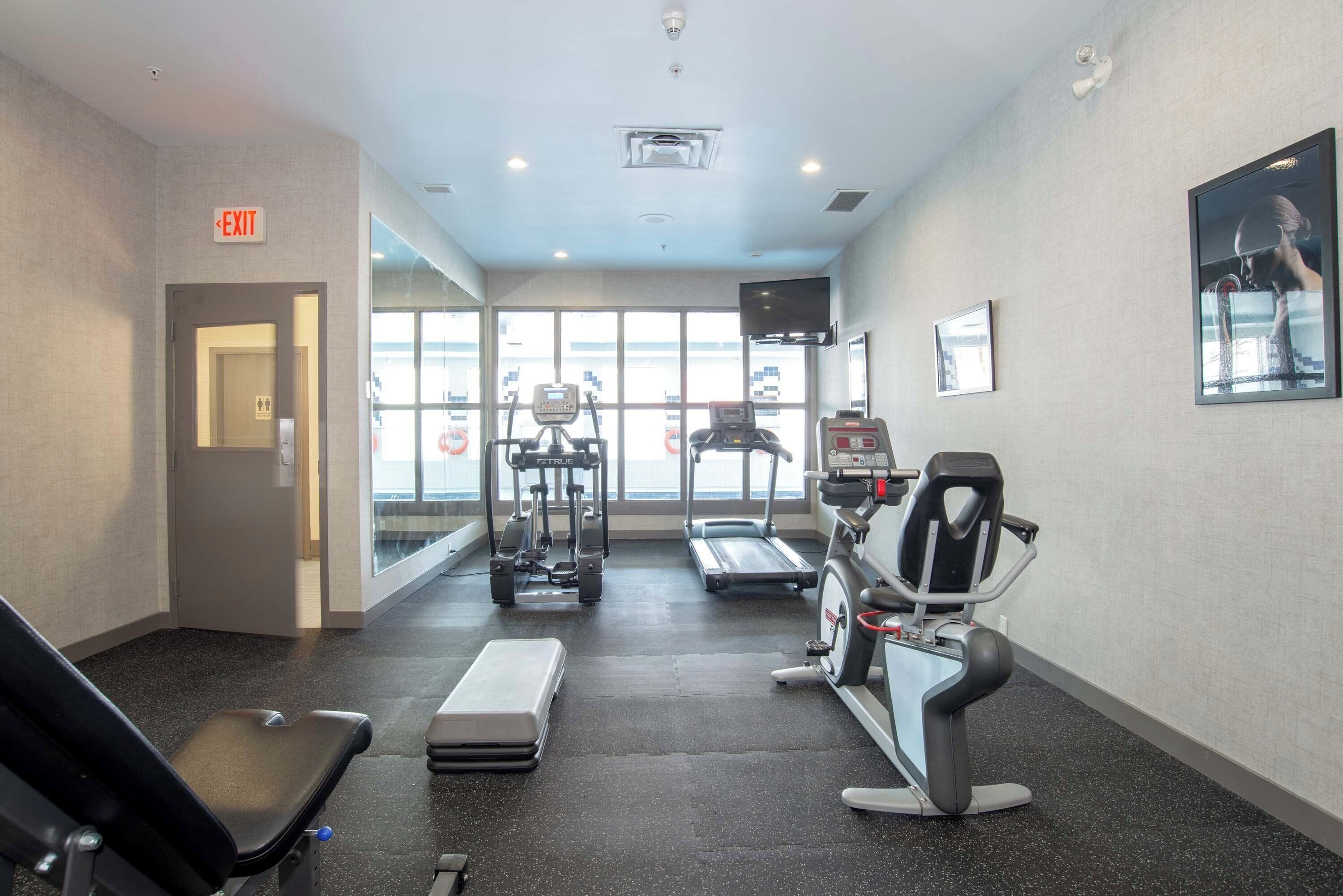 Une salle de sport équipée de tapis de course, de vélos elliptiques et d’un vélo d’appartement.