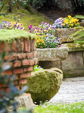 A garden with stone planters containing a variety of flowers. - Hotel Casa del Marqués (Santillana del Mar)