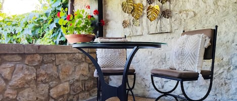 Un muro de piedra, una mesa con sillas y decoración de hojas en la pared.