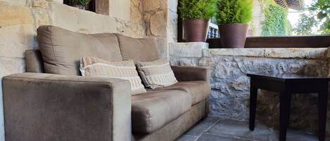 A stone wall, a brown sofa with patterned cushions, and a wooden table.