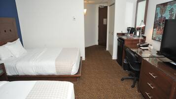A hotel room with a bed, a desk, a chair, a dresser, a television, and a painting on the wall.