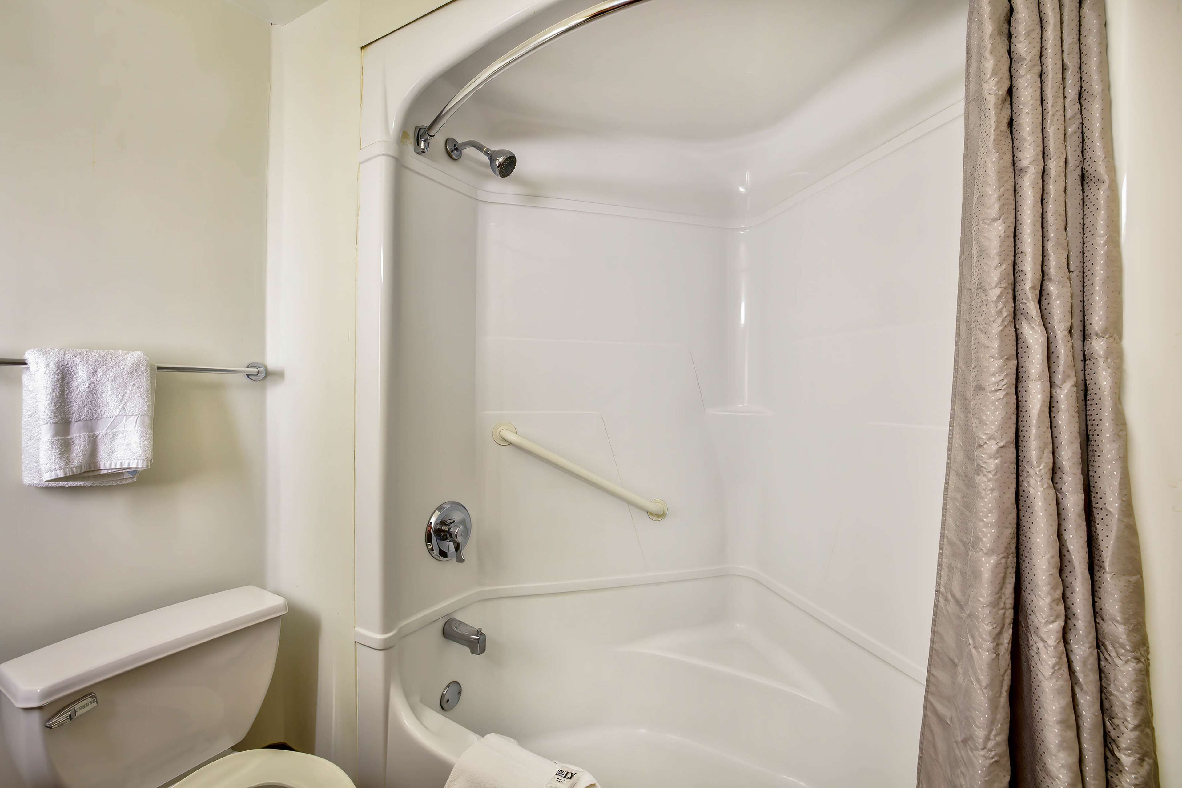 A bathroom with a bathtub, toilet, and a towel rack.