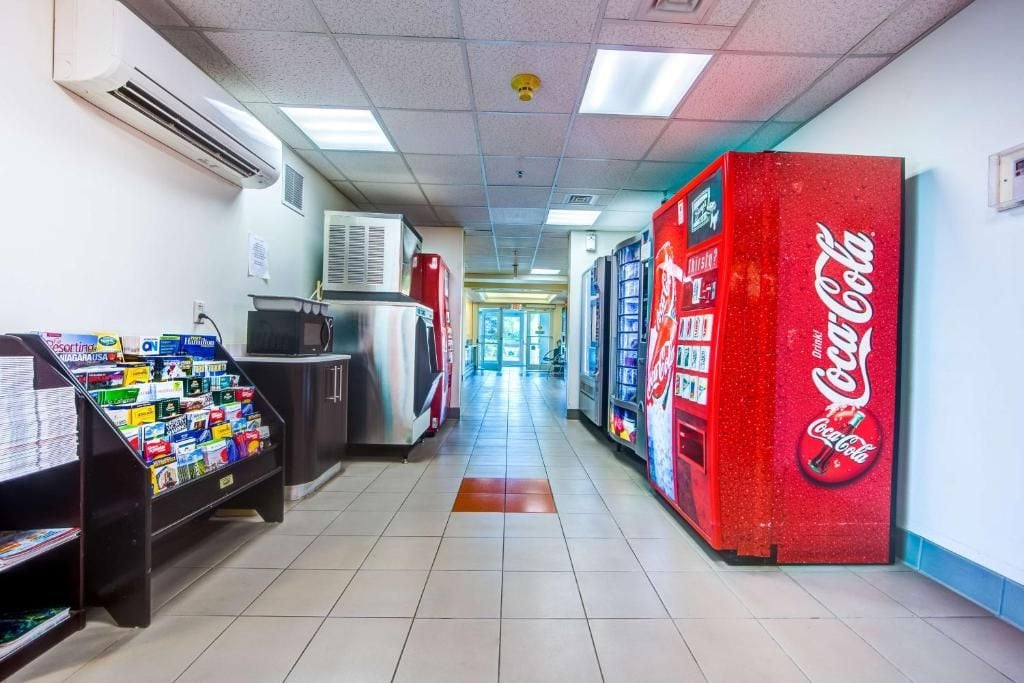A hallway with vending machines, a refrigerator, and a Coca-Cola vending machine.