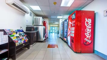 A hallway with vending machines, a refrigerator, and a Coca-Cola vending machine.