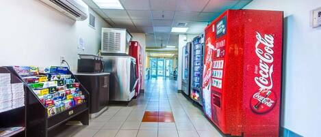 A hallway with vending machines, a refrigerator, and a Coca-Cola vending machine.