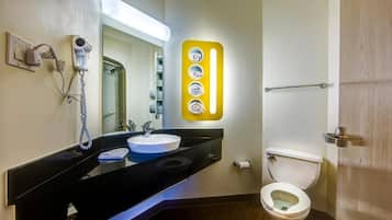 Une salle de bain avec un meuble-lavabo noir, un lavabo blanc, un sèche-cheveux et des toilettes.